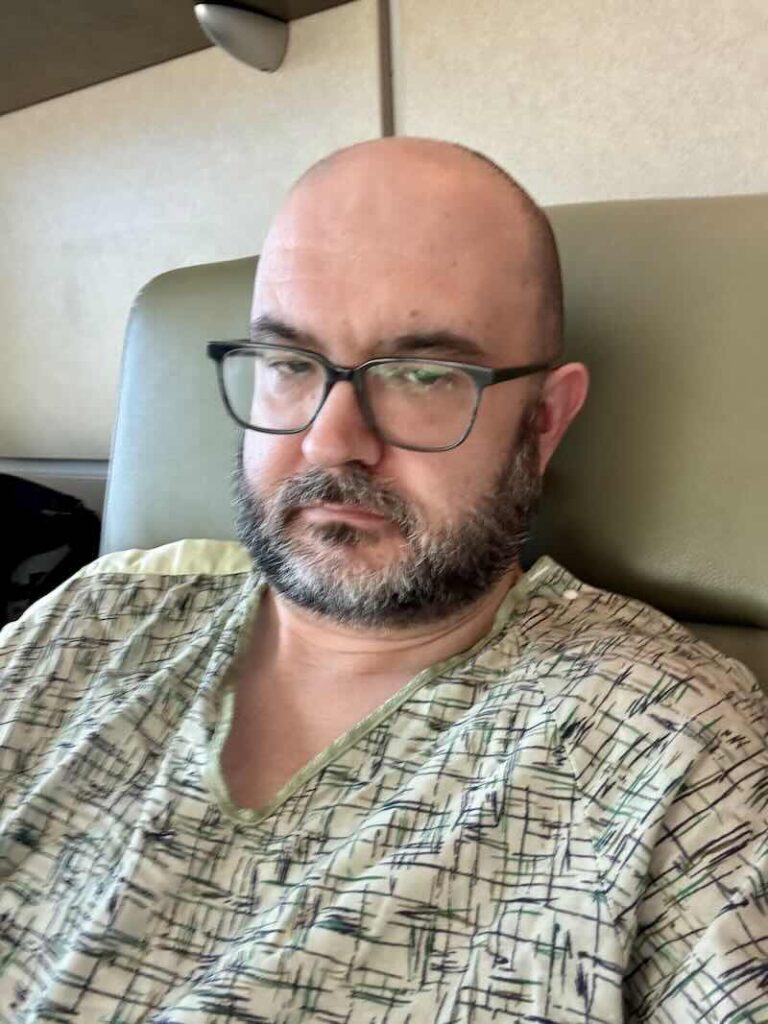 Doug, wearing a green hospital gown. He looks annoyed.
